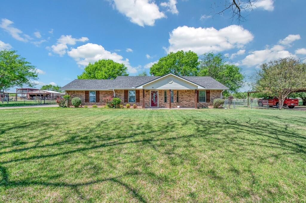 Single story home featuring a porch, brick siding, and a detached carport