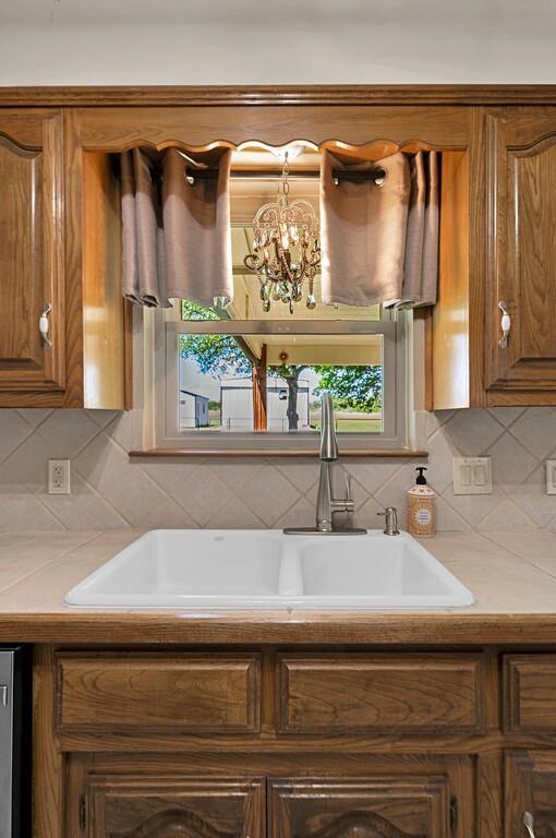 2857 Country Spring Road Lorena, TX 76655 - Photo 11 of 40 Kitchen featuring light countertops, wood finish cabinets, backsplash, and a chandelier