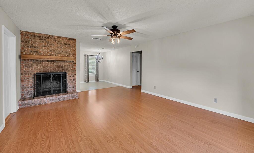 2857 Country Spring Road Lorena, TX 76655 - Photo 3 of 40 Unfurnished living room with light wood-style flooring, a textured ceiling, a ceiling fan, and a brick fireplace