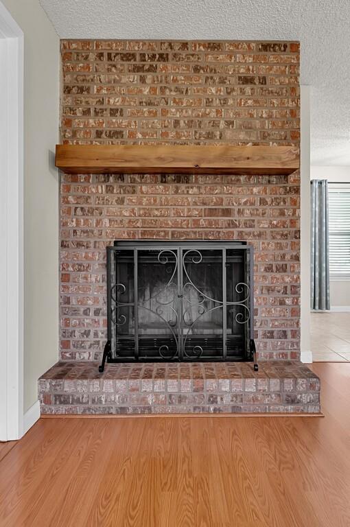 2857 Country Spring Road Lorena, TX 76655 - Photo 5 of 40 Detailed view of a textured ceiling, a brick fireplace, and wood finished floors