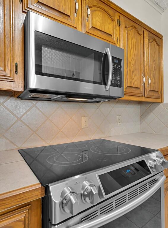 2857 Country Spring Road Lorena, TX 76655 - Photo 9 of 40 Kitchen featuring stainless steel appliances, light countertops, wood finish cabinetry, and tasteful backsplash