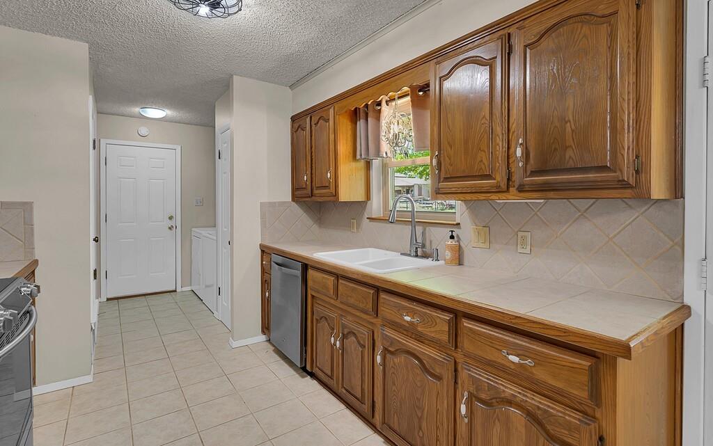 2857 Country Spring Road Lorena, TX 76655 - Photo 10 of 40 Kitchen with wood finish cabinetry, tasteful backsplash, tile counters, stainless steel appliances, and light tile patterned flooring