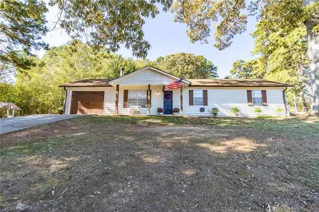 a front view of house with yard and trees in the background