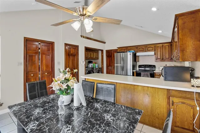 a kitchen with stainless steel appliances kitchen island granite countertop a refrigerator a stove top oven a sink with dining table and chairs