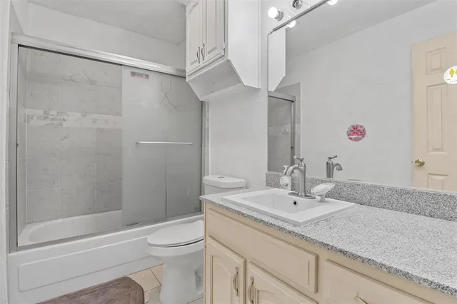 a bathroom with a granite countertop sink a toilet and shower