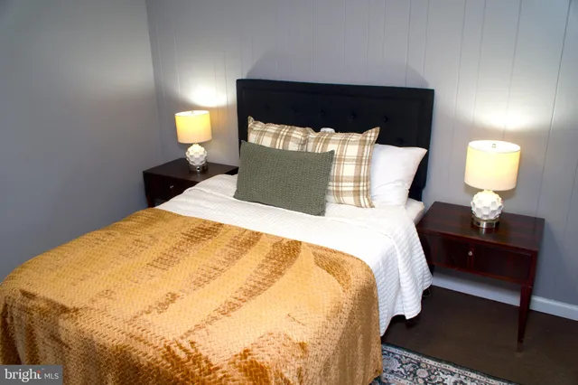 a bedroom with a bed and a lamp on dresser