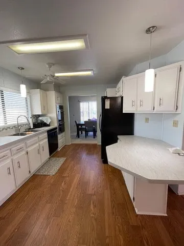 a large kitchen with kitchen island a sink dishwasher a stove a refrigerator and white cabinets with wooden floor