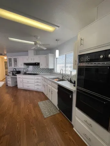 a large kitchen with granite countertop a stove top oven and cabinets