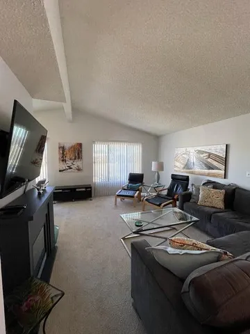 a living room with furniture a flat screen tv and a window