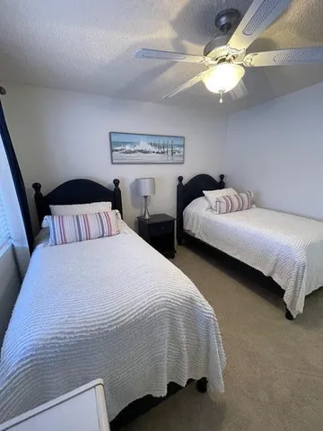 a bedroom with two beds and a ceiling fan