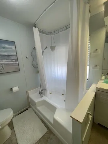 a white toilet sitting next to a white sink and vanity