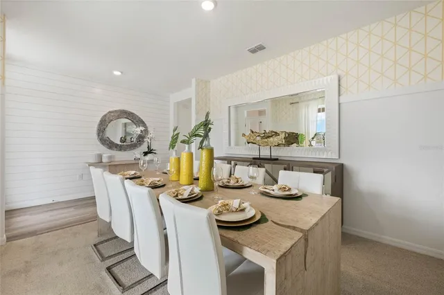 a kitchen with white cabinets a sink a stove a dining table and chairs