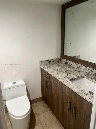a bathroom with a granite countertop toilet and a sink