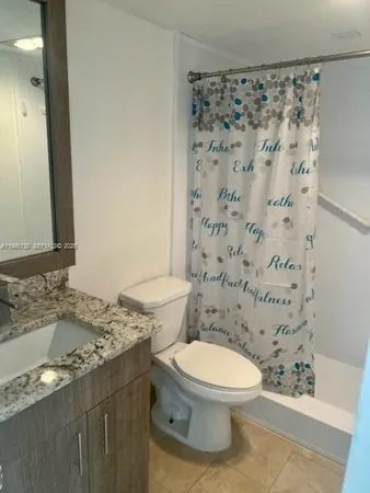 a bathroom with a granite countertop toilet a sink and a mirror