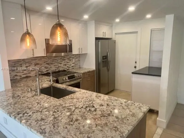a kitchen with stainless steel appliances kitchen island a stove a refrigerator and a sink
