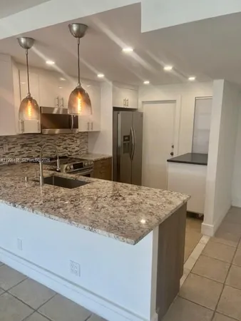 a kitchen with kitchen island granite countertop wooden cabinets a stove and a refrigerator