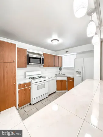 a large kitchen with cabinets a sink and white appliances