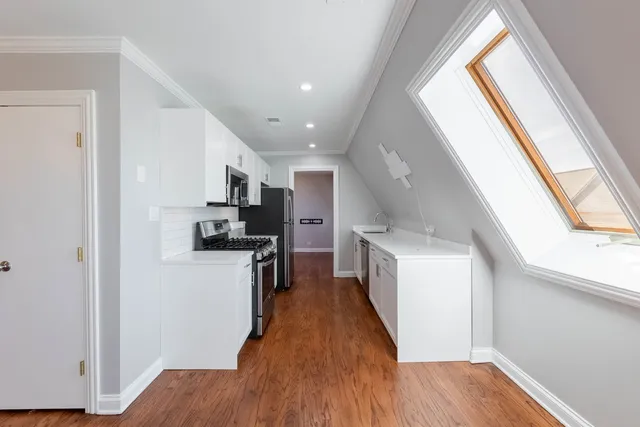 a kitchen with a refrigerator a stove top oven and wooden floor