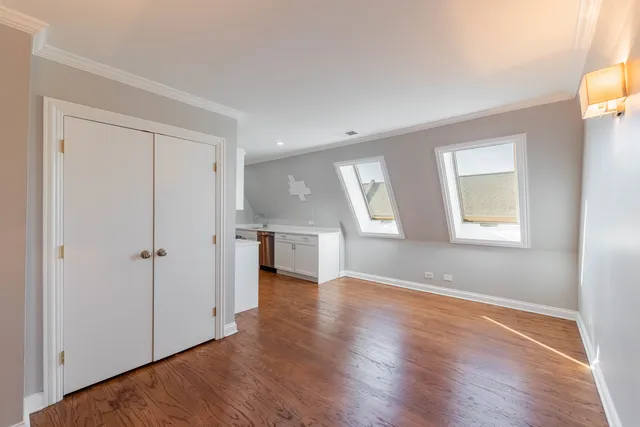 an empty room with wooden floor cabinet and windows