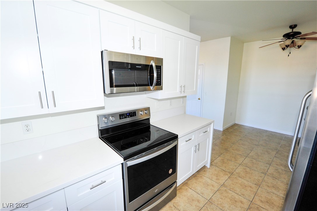 231 West Horizon Ridge Parkway, Unit 1113 Henderson, NV 89012 - Photo 11 of 23 Kitchen featuring stainless steel appliances, white cabinetry, light tile patterned flooring, and ceiling fan