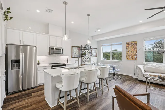 a kitchen with stainless steel appliances granite countertop a stove a refrigerator a kitchen island a table and chairs