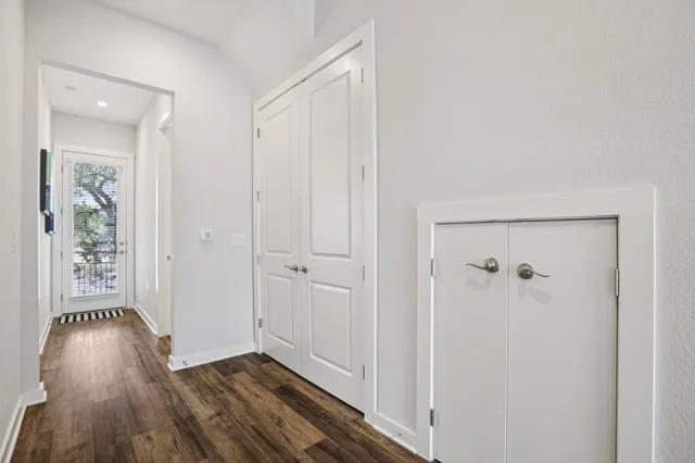a view of a hallway with wooden floor and a bathroom