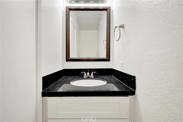 a bathroom with a granite countertop sink and a mirror