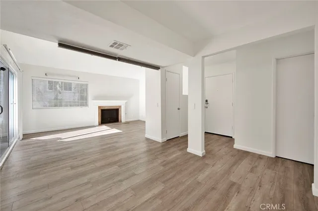 a view of empty room with wooden floor and fireplace