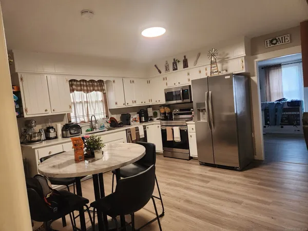 a kitchen with stainless steel appliances a dining table chairs refrigerator and microwave