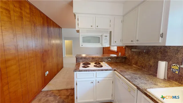 a kitchen with white cabinets and white appliances