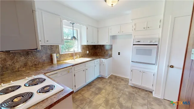 a kitchen with white cabinets and appliances