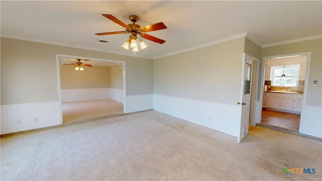 an empty room with chandelier fan and windows
