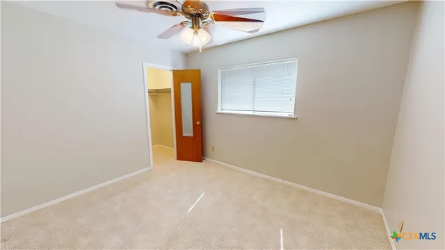 an empty room with a window and a chandelier fan