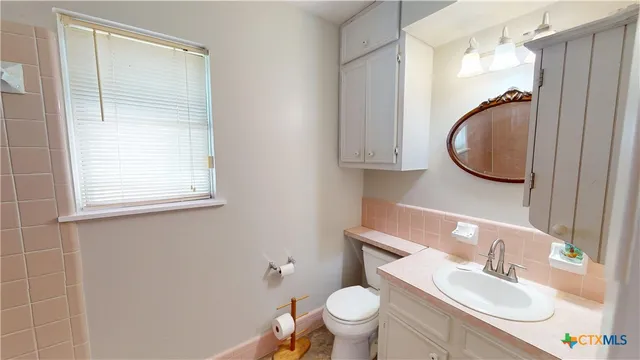 a bathroom with a granite countertop toilet sink and mirror