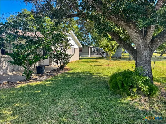 a view of a house with a big yard and large trees