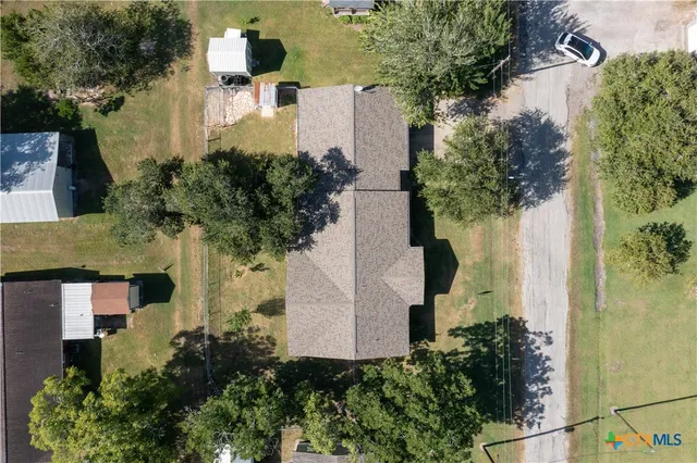 an aerial view of a house with a yard and large trees
