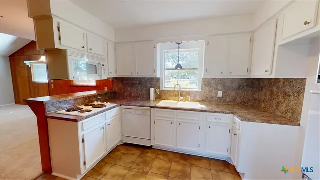 a kitchen with granite countertop a sink stove and cabinets