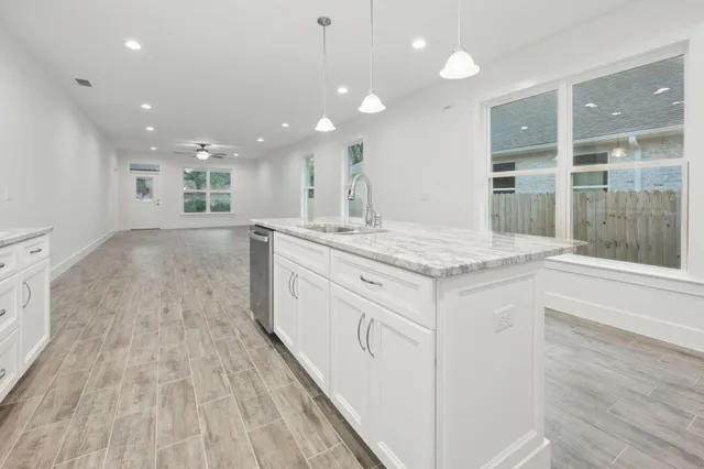 a view of granite countertop kitchen island a sink wooden floor and a window