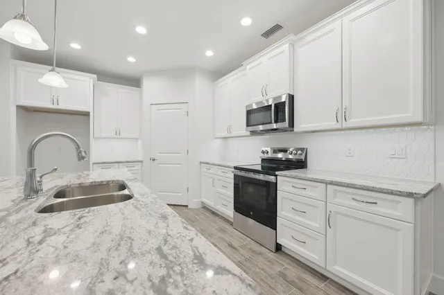 a kitchen with granite countertop white cabinets and stainless steel appliances