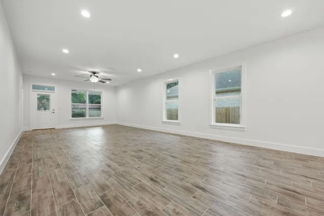 an empty room with wooden floor and windows
