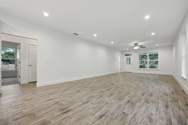 an empty room with wooden floor and windows