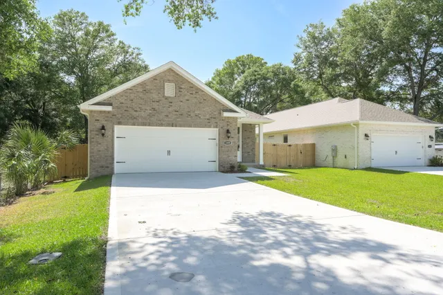 a view of a white house with a yard and large tree