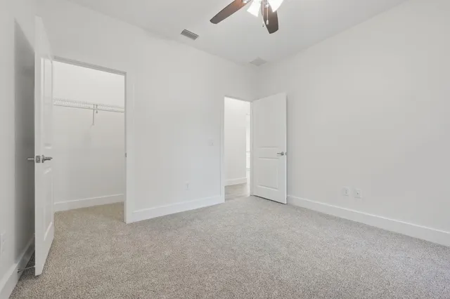 an empty room with windows and ceiling fan