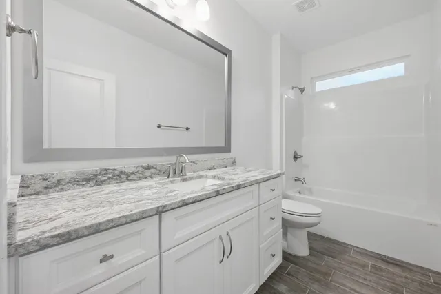 a bathroom with a granite countertop toilet sink and mirror