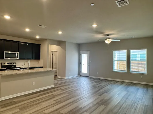 a view of a kitchen with a sink a refrigerator wooden floor and a window