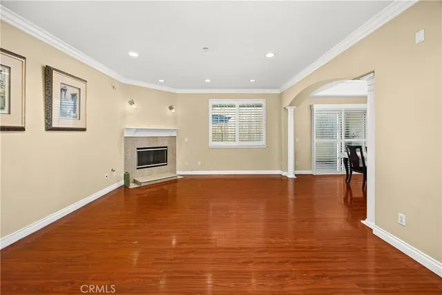 a view of an empty room with wooden floor fireplace and a window
