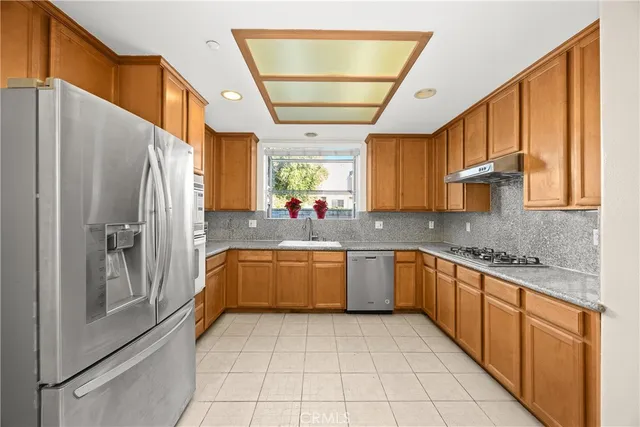 a kitchen with stainless steel appliances granite countertop a refrigerator and a stove top oven