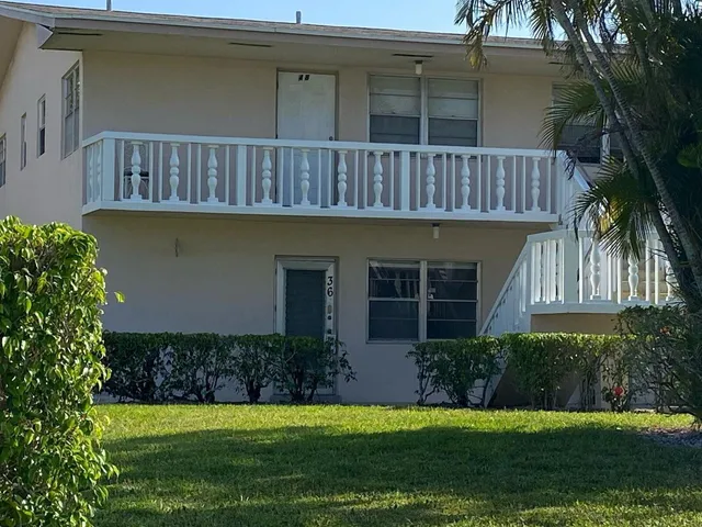 a front view of a house with a yard and potted plants