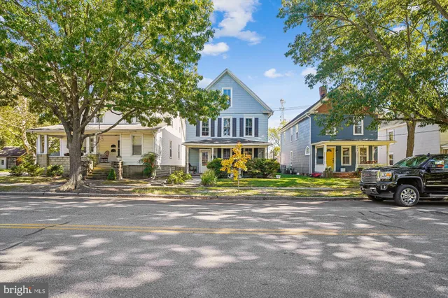 a view of a big house with a large tree and plants