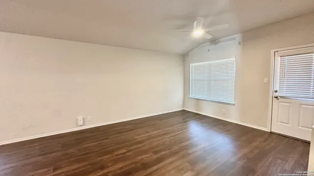 a view of an empty room with wooden floor and a window